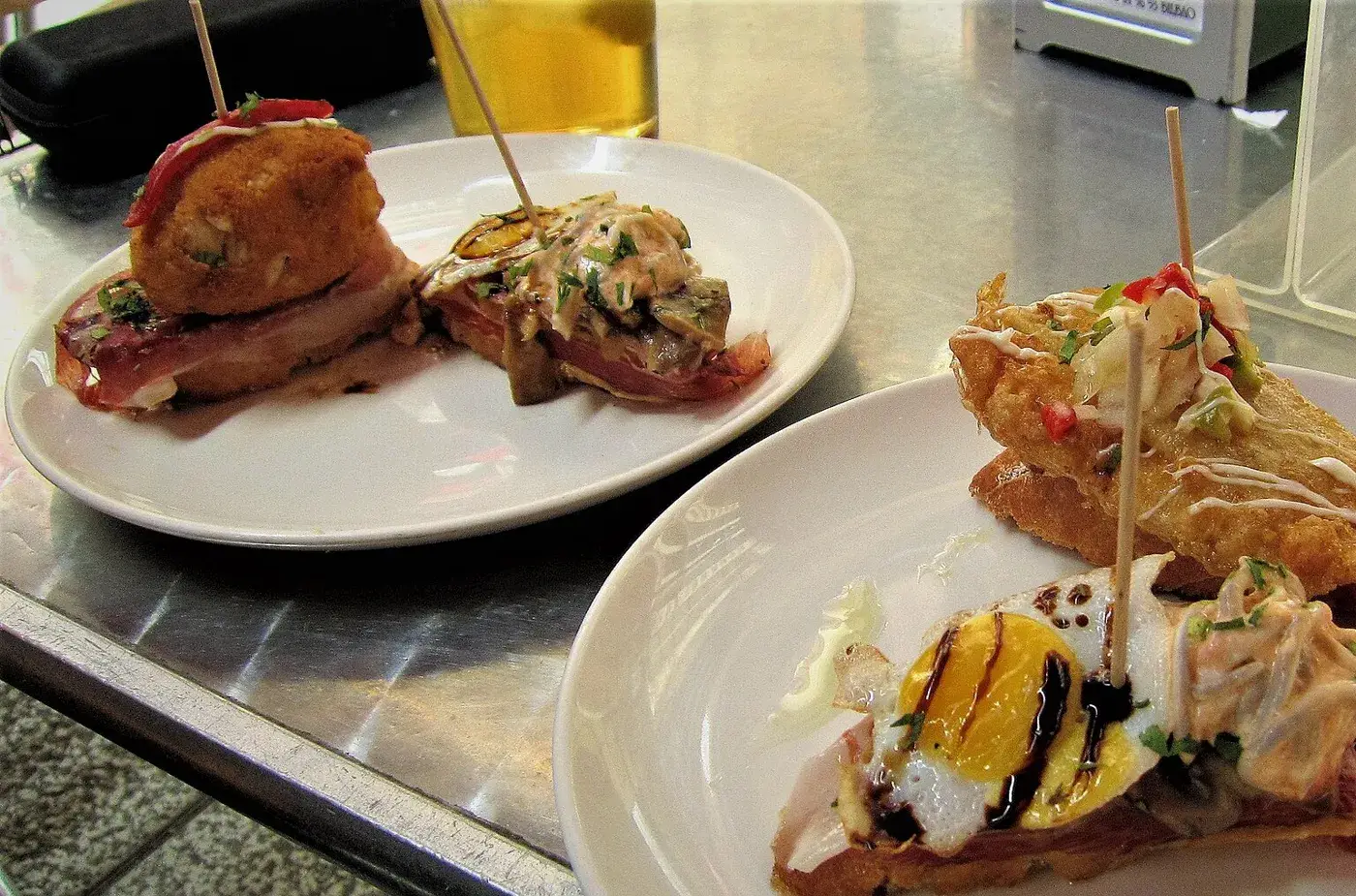 Pintxos served on plates with toothpicks at a bar in Bilbao